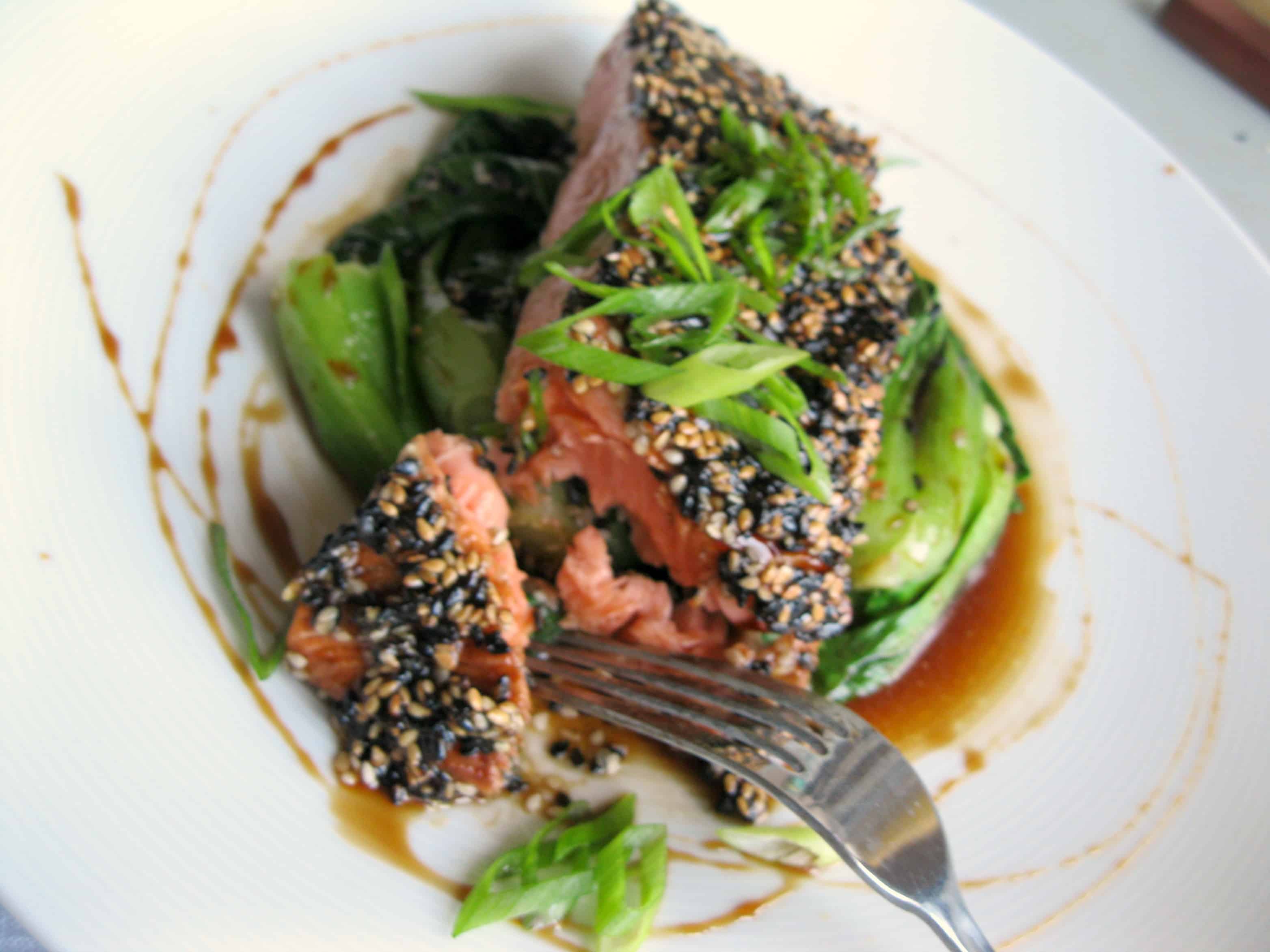 A fork cutting a bit of sesame crusted salmon.