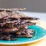 Close up side view of a stack of everything bagel seasoned quinoa crackers.