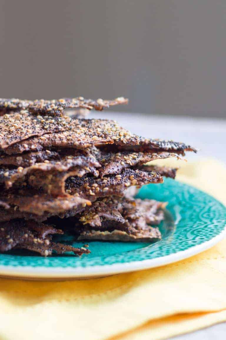 Close up side view of a stack of everything bagel seasoned quinoa crackers.
