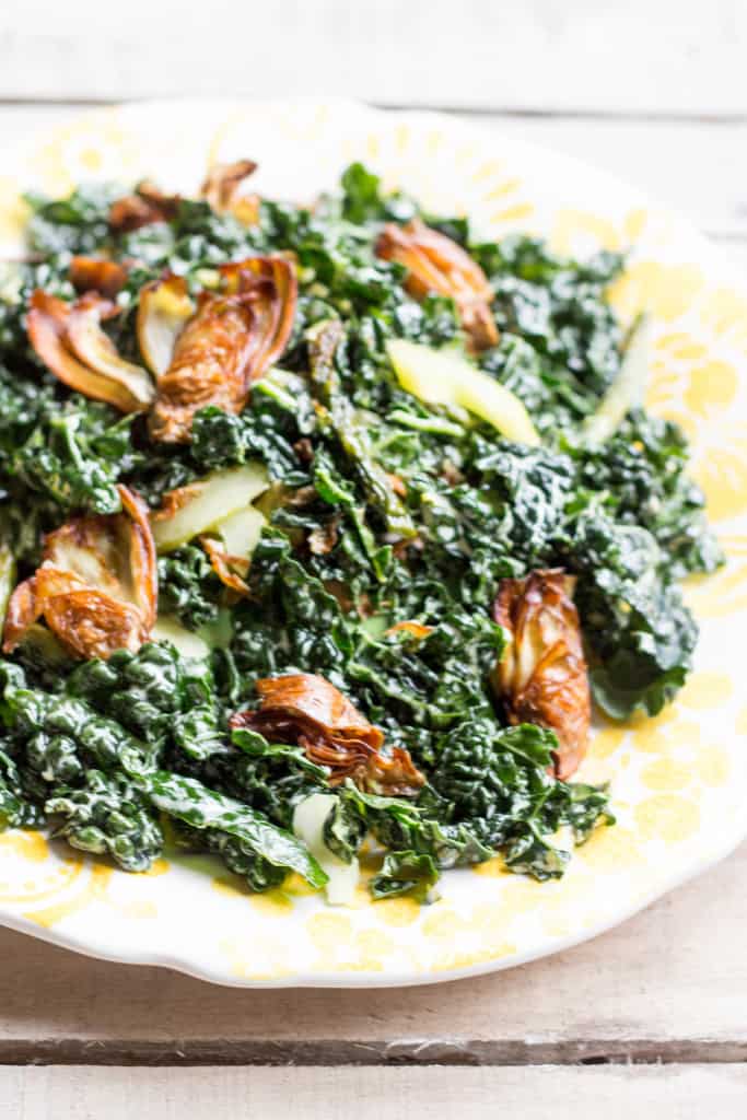 Close up of wilted kale and pickled celery salad topped with fried artichoke.