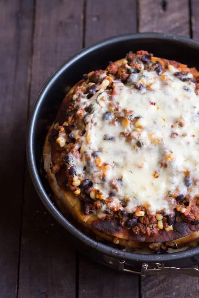 Top view of melted cheese over taco cake in a springform pan.