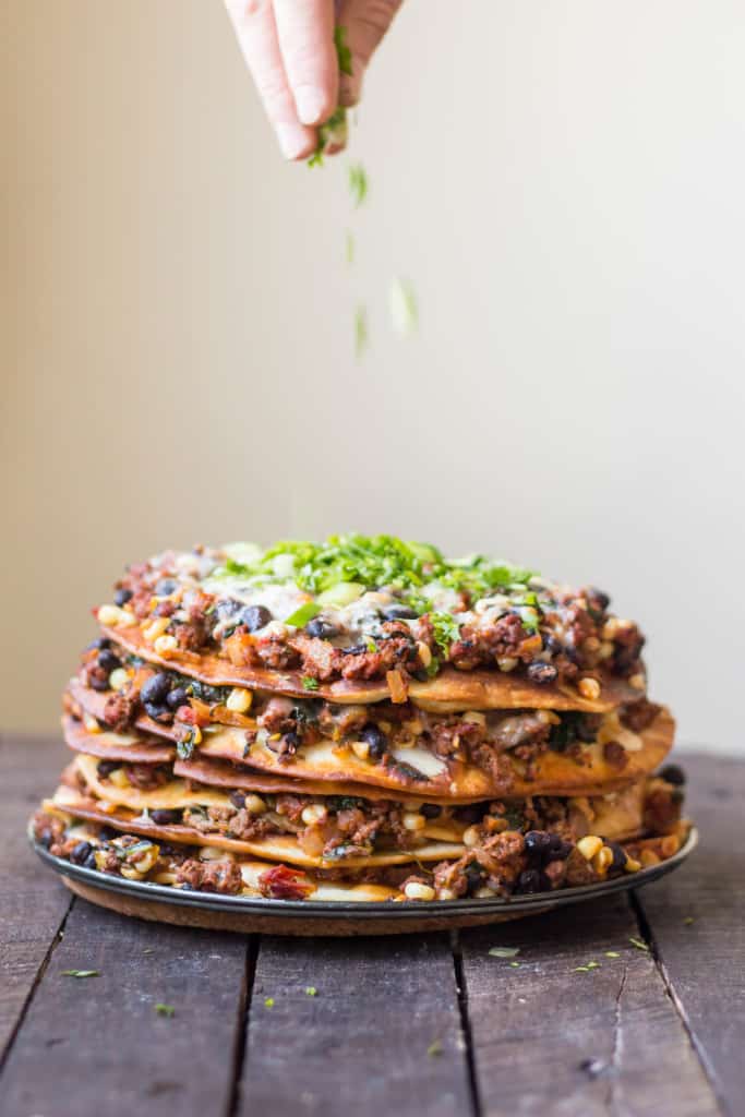 Taco cake sitting on a springform pan bottom on a wood table.