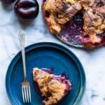 A blue plate with a piece of plum torte and a fork.