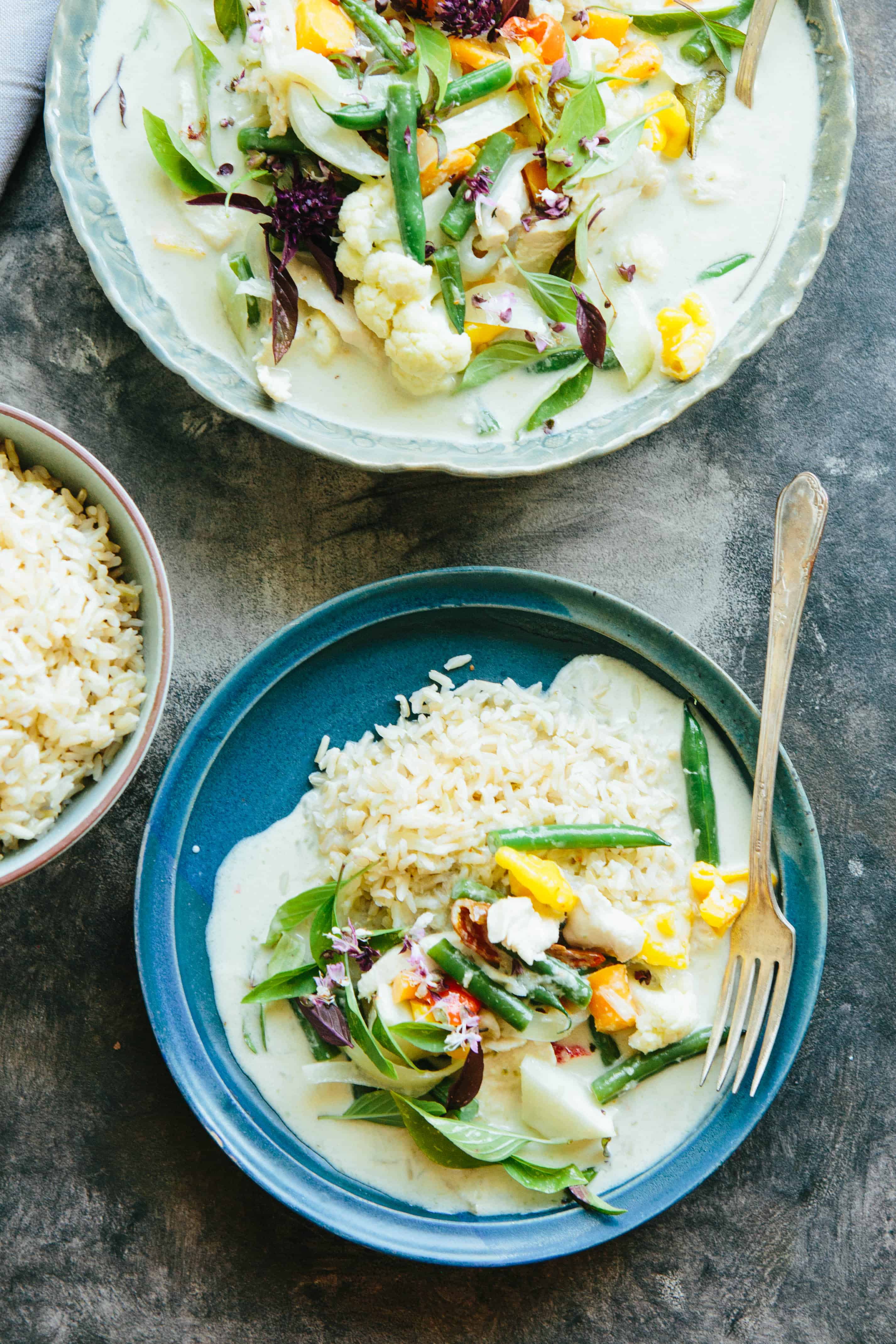 A blue dinner plate with white rice and Thai green curry.