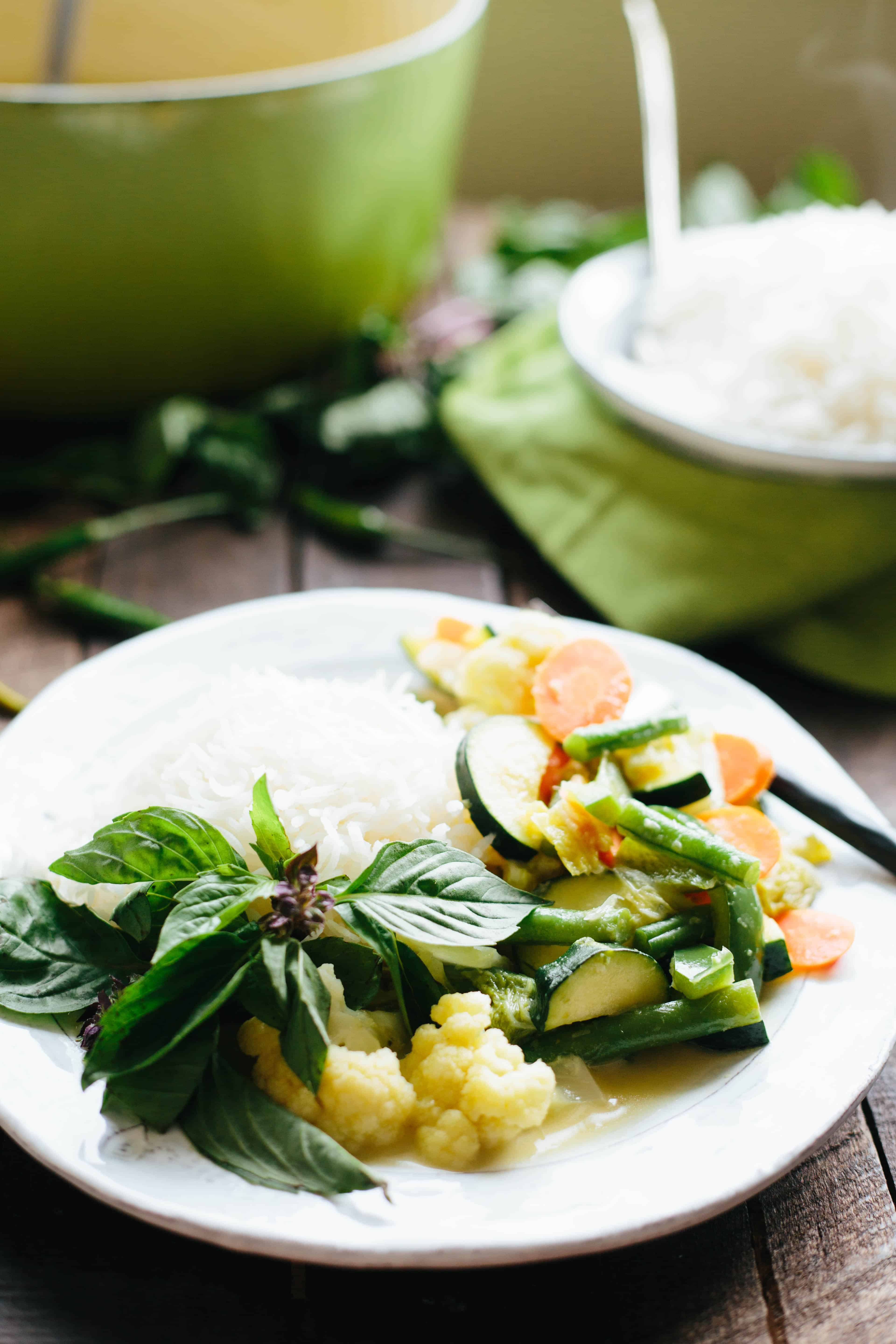 Close up shot of a white dinner plate filled with white rice and Thai green curry.