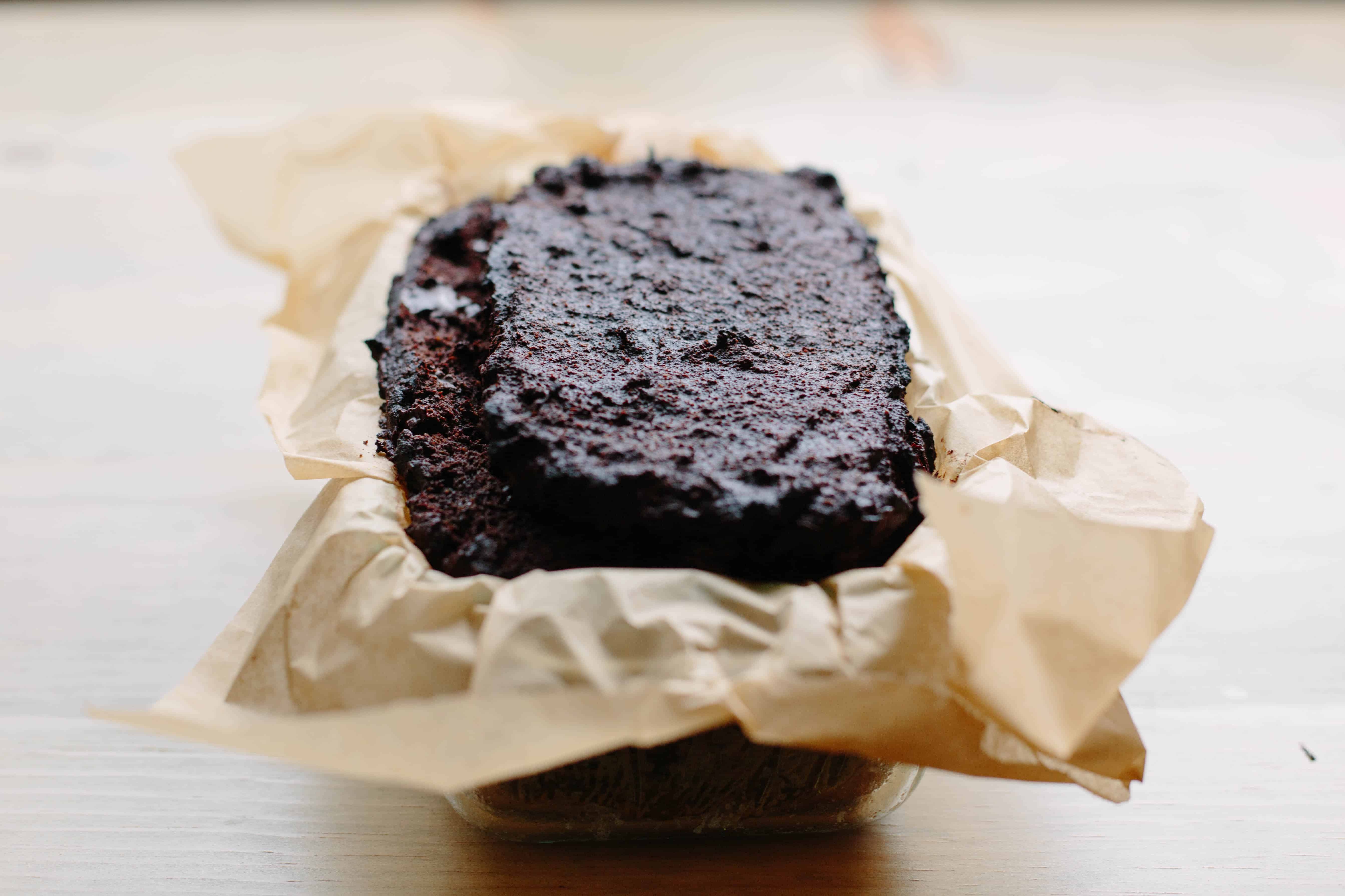 A loaf of Paleo chocolate banana bread in a parchment lined loaf pan.