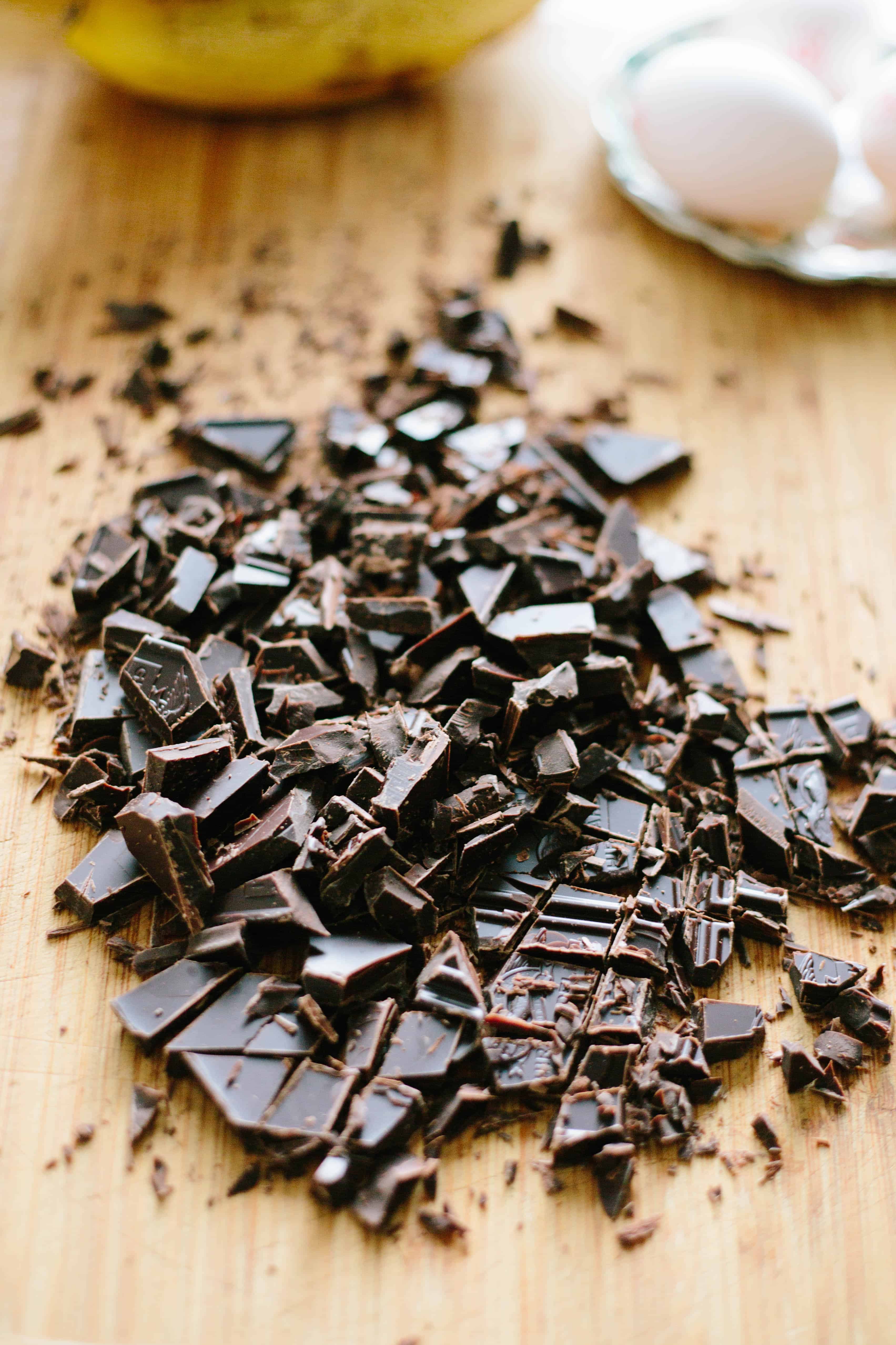 Roughly chopped chocolate on a wood cutting board.