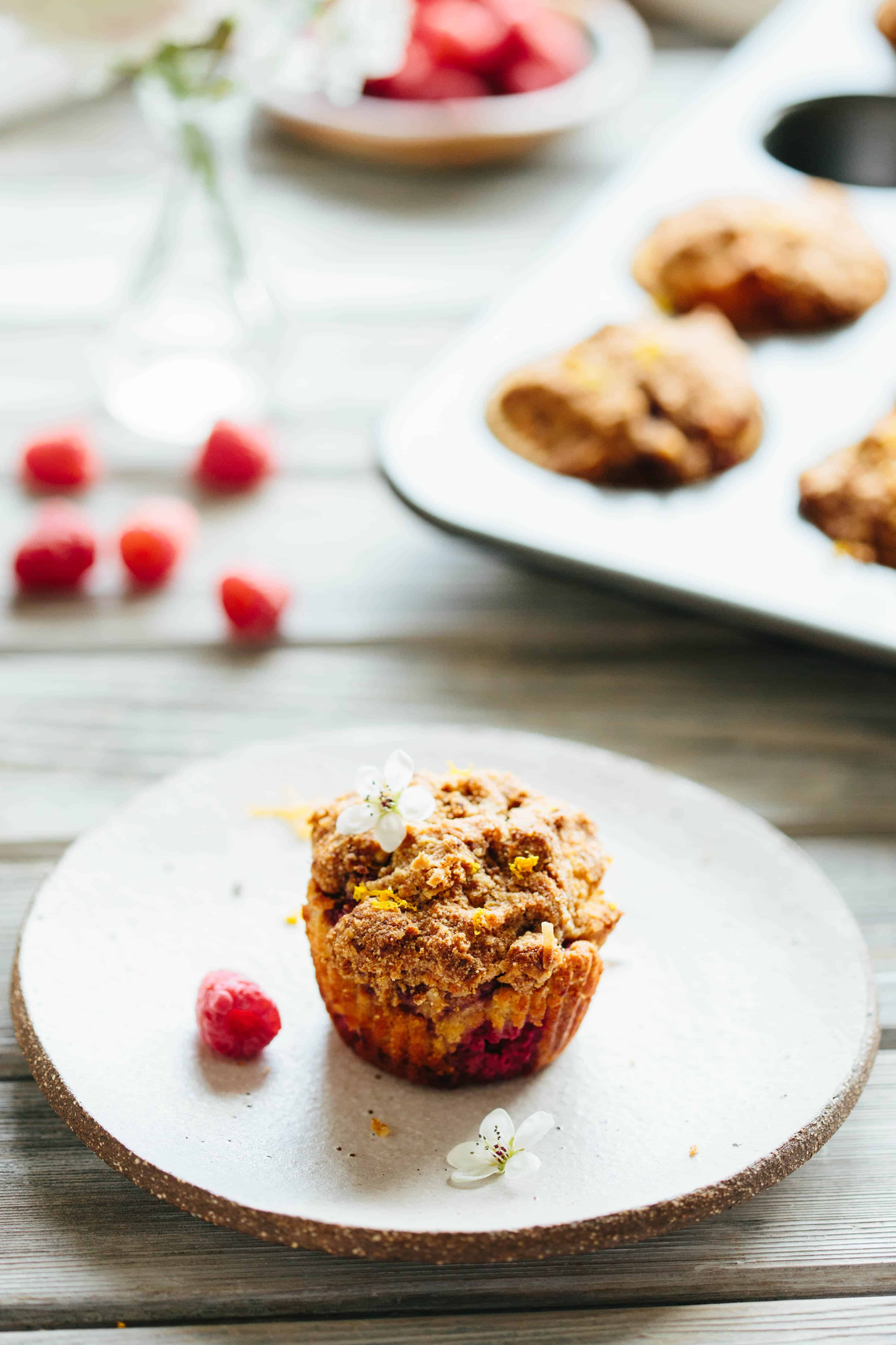 A single Paleo orange raspberry crumb muffin on a white plate.