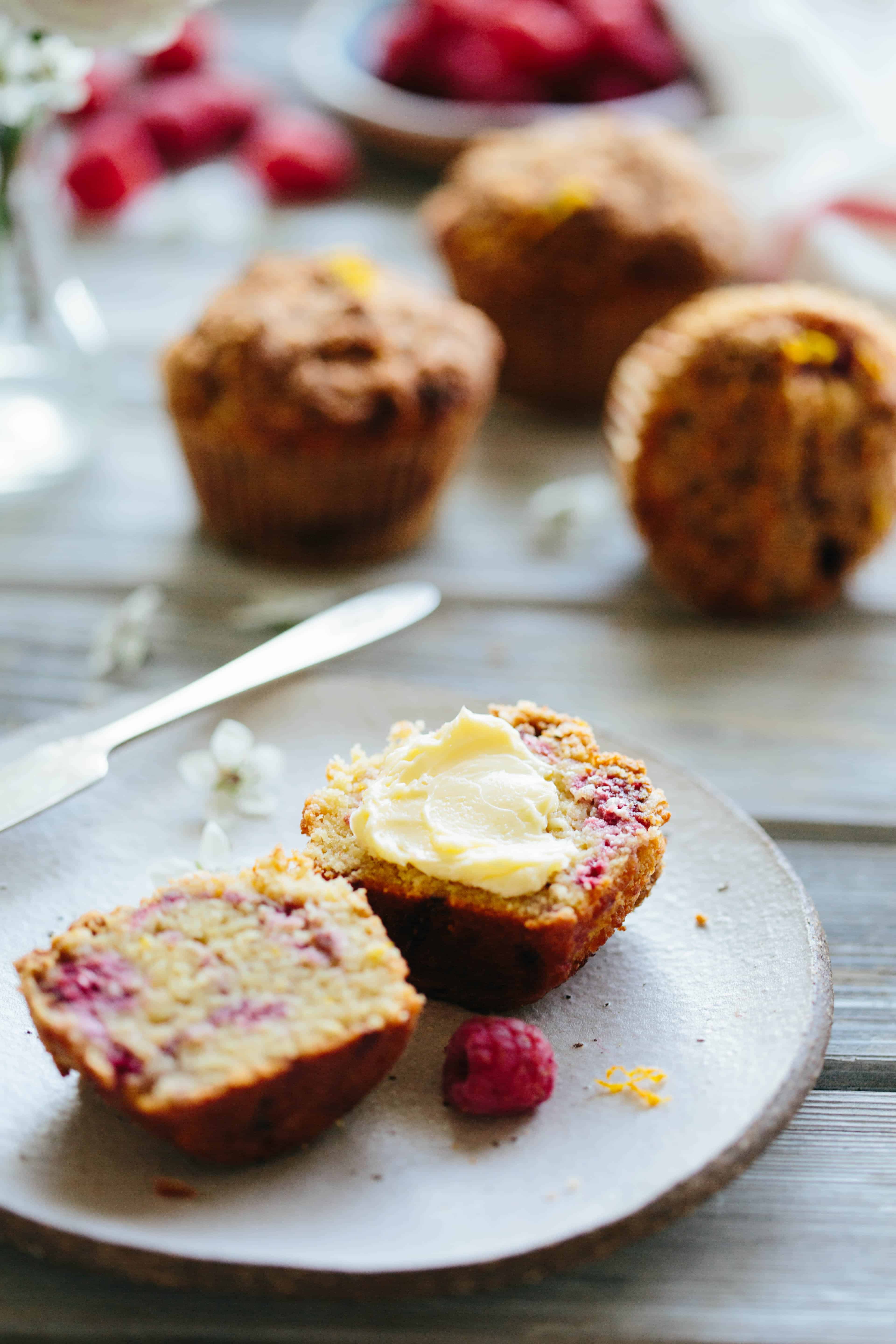 Close up of a Paleo orange raspberry muffin split in half and buttered.