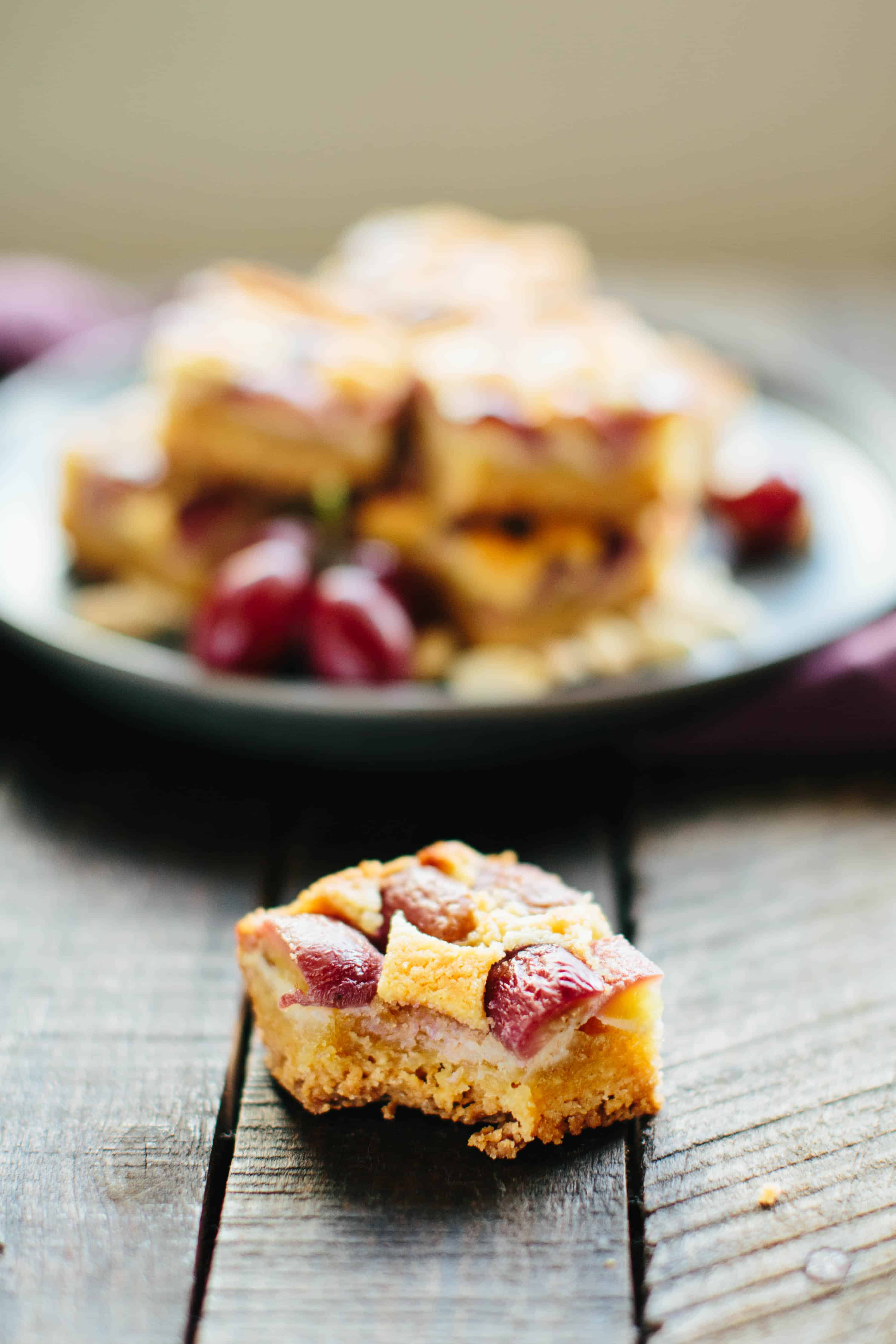 Peanut butter shortbread bar with a bite taken out of it sitting in front of a plate of more bars.