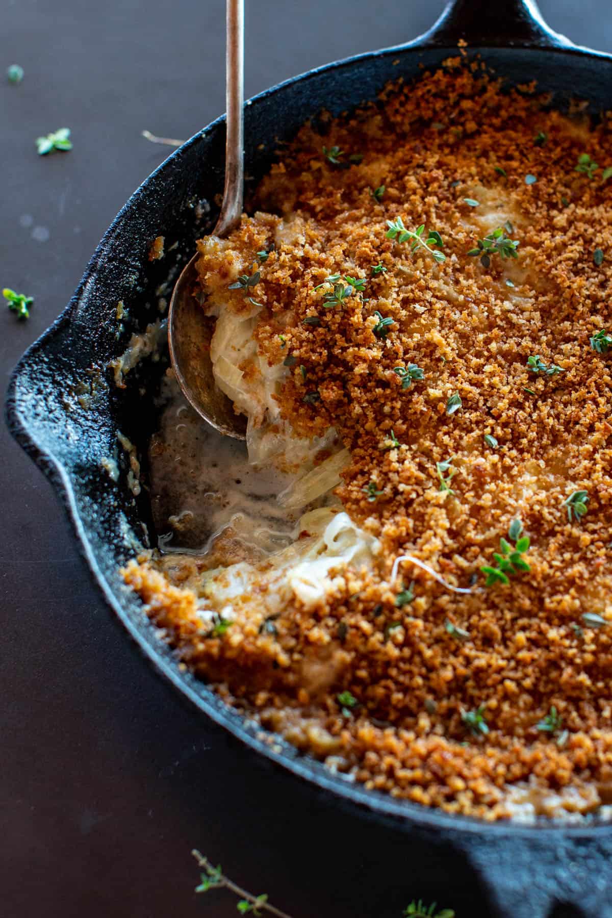 fennel onion gratin in a cast iron skillet with spoon and scoop taken out