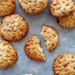 broken pignoli cookie on a gray surface surrounded by more cookies