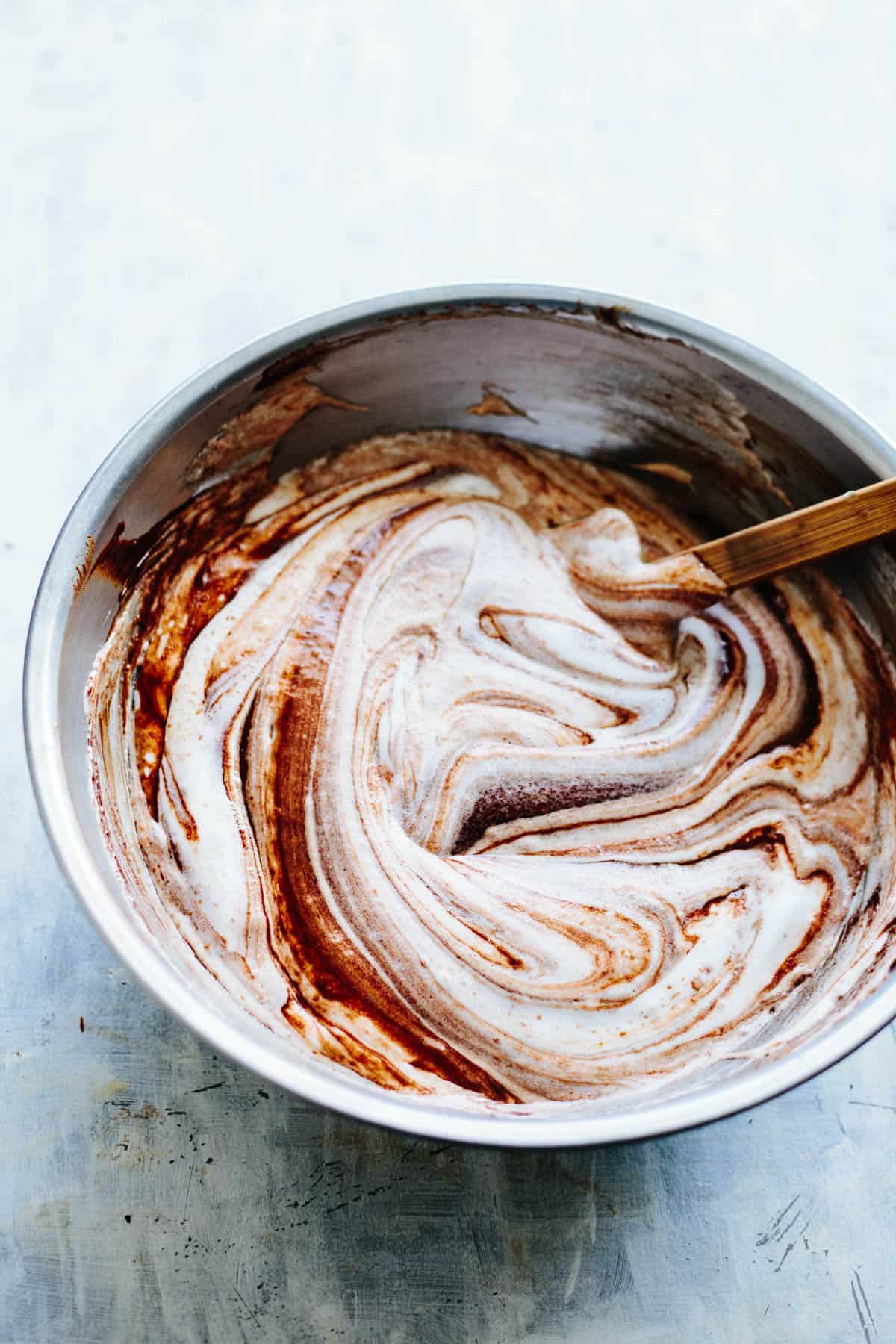 A mixing bowl where whipped egg whites are being stirred into chocolate batter for souffle.
