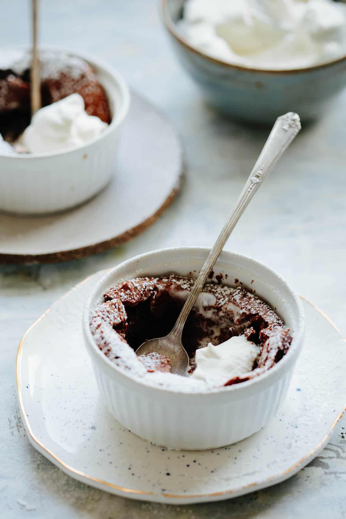 A spoon digging into a flourless chocolate souffle in a ramekin.