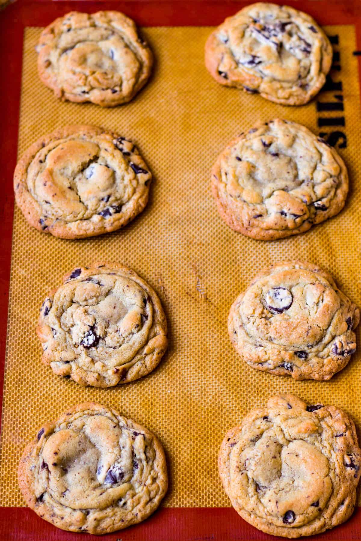 Top view of baked chewy chocolate chunk cookies on a silpat lined baking sheet.