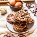 a plate of cookies with a broken cookie in the foreground and ingredients in the background