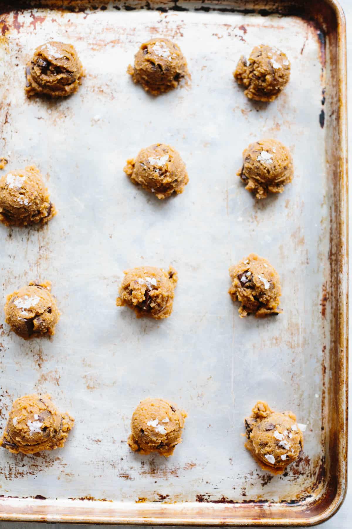Paleo chocolate chip cookie dough balls on a baking sheet waiting to go in the oven.