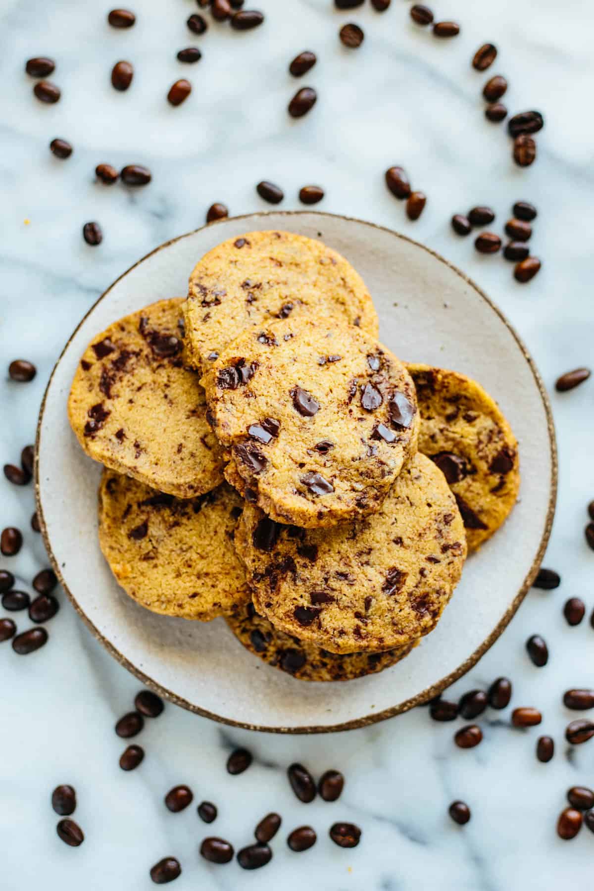 overhead shot of plate of chocolate chip shortbread cookies with espresso beans scattered around