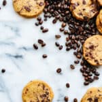 overhead shot of a marble table with random cookies in the corner and lots of scattered coffee beans