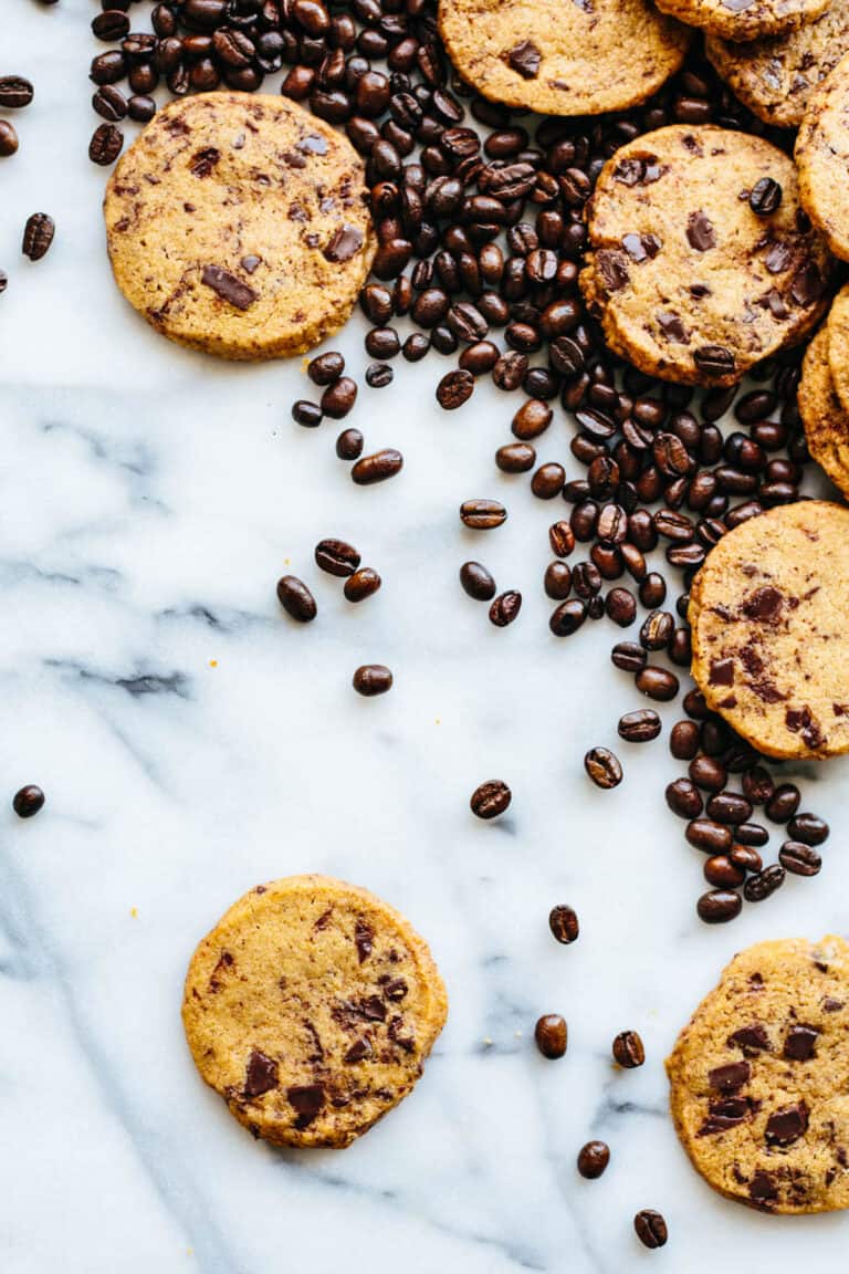 overhead shot of a marble table with random cookies in the corner and lots of scattered coffee beans