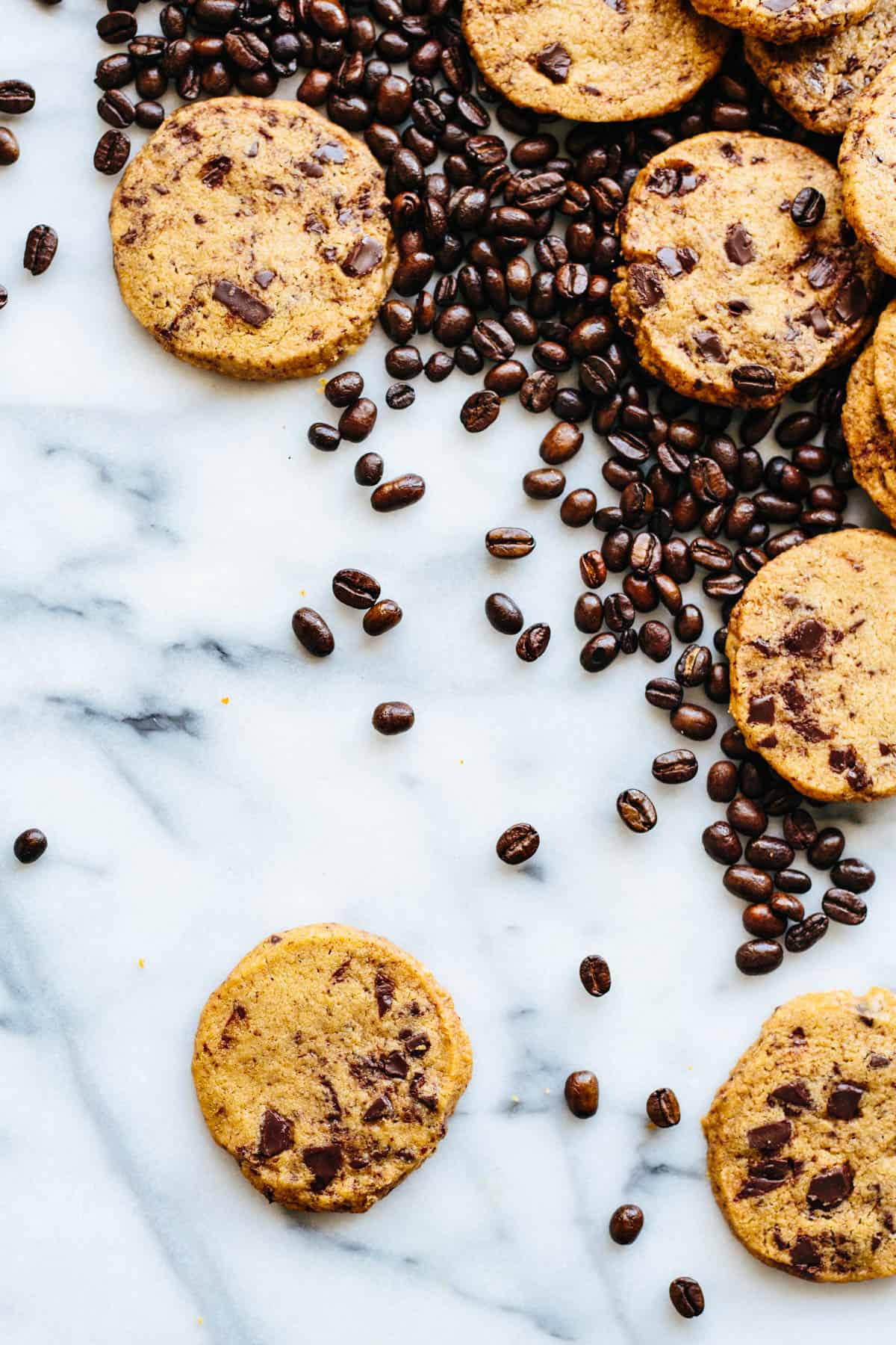 overhead shot of a marble table with random cookies in the corner and lots of scattered coffee beans