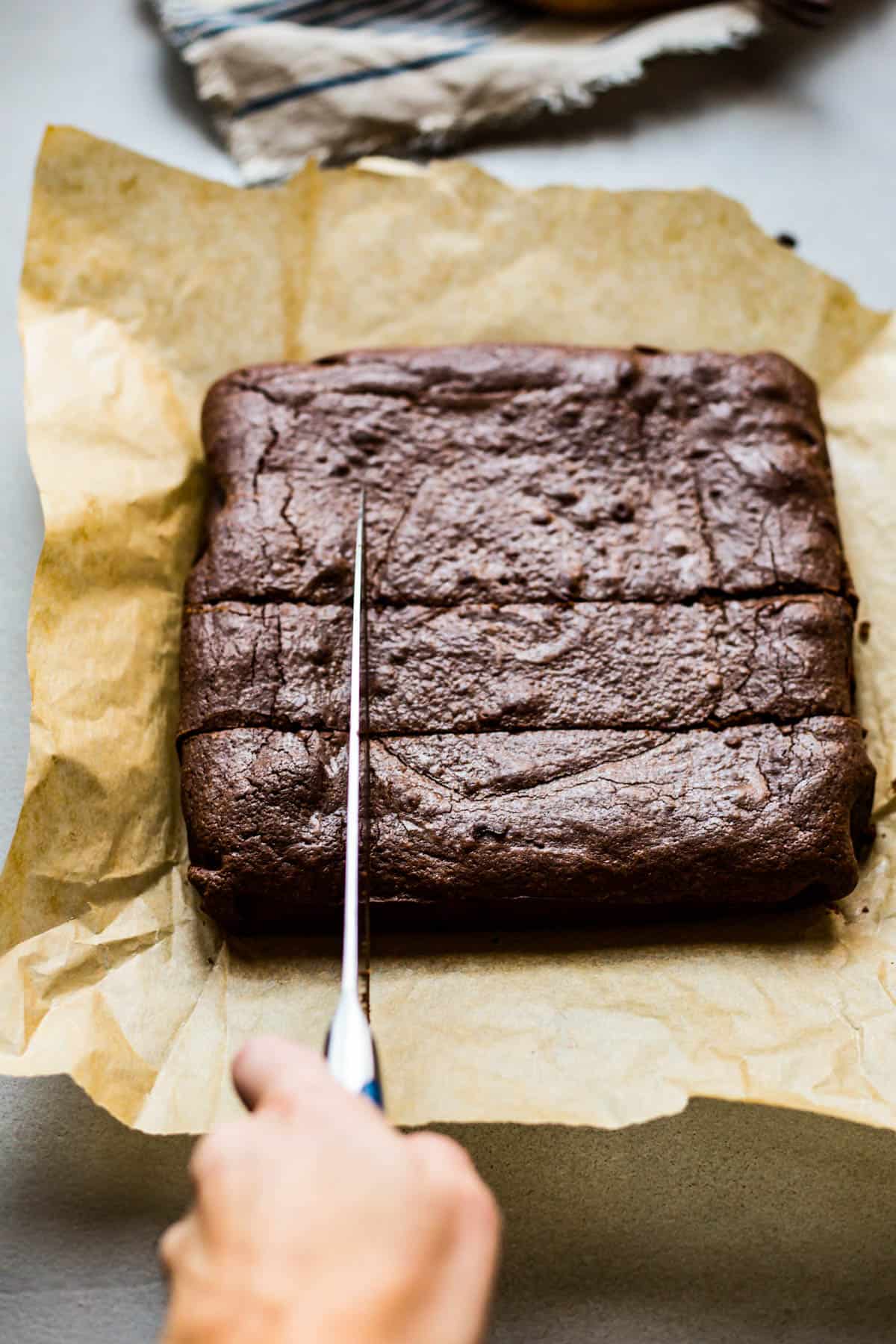 a knife cutting a batch of brownies into squares