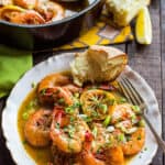 a white plate with shrimp, lemon and bread