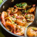close up of a pan with saucy bbq shrimp with a serving spoon