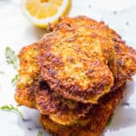 A stack of thin crispy Italian breaded chicken breasts with a lemon.