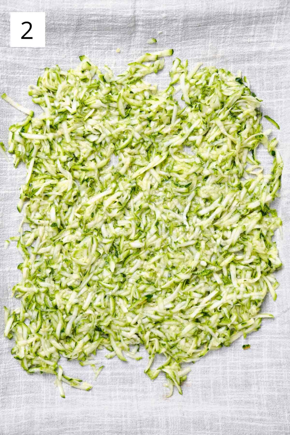 Grated zucchini draining on a kitchen towel.