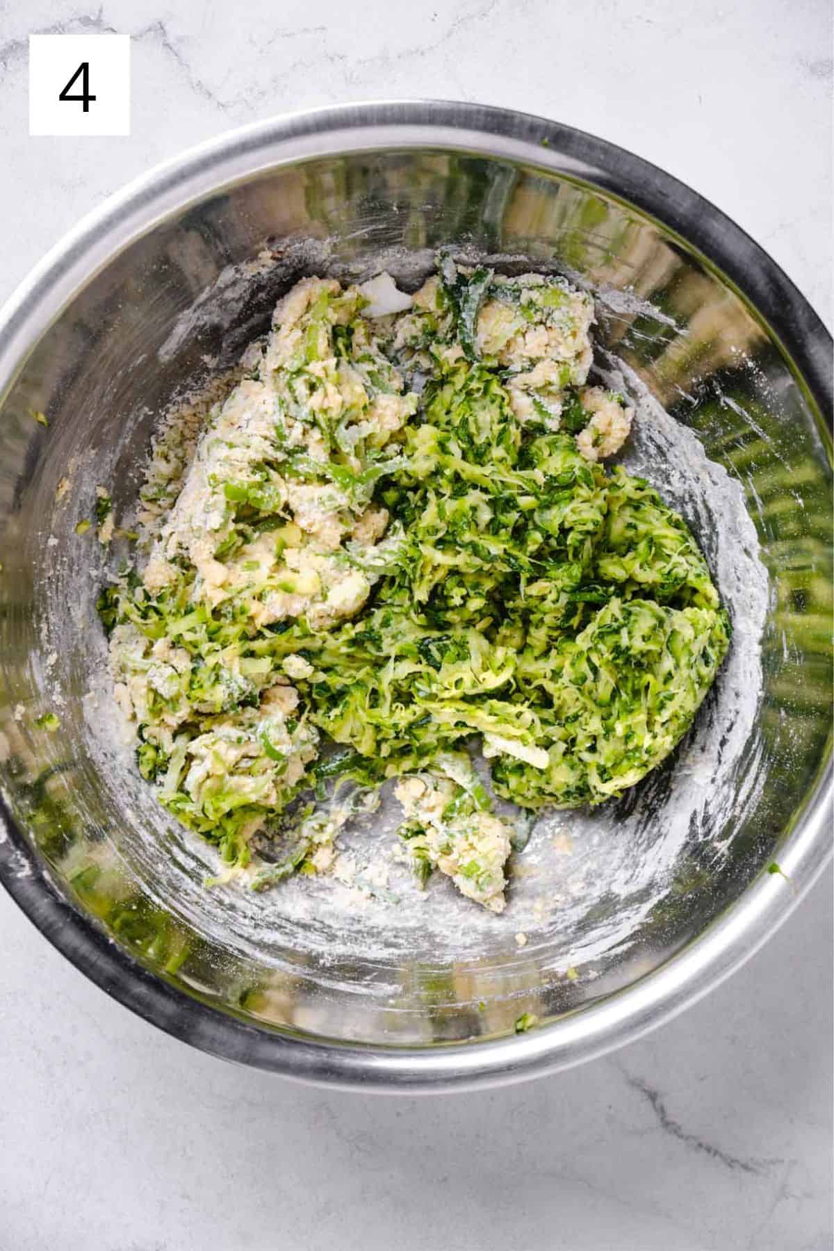 Grated zucchini being mixed into a bowl of batter.
