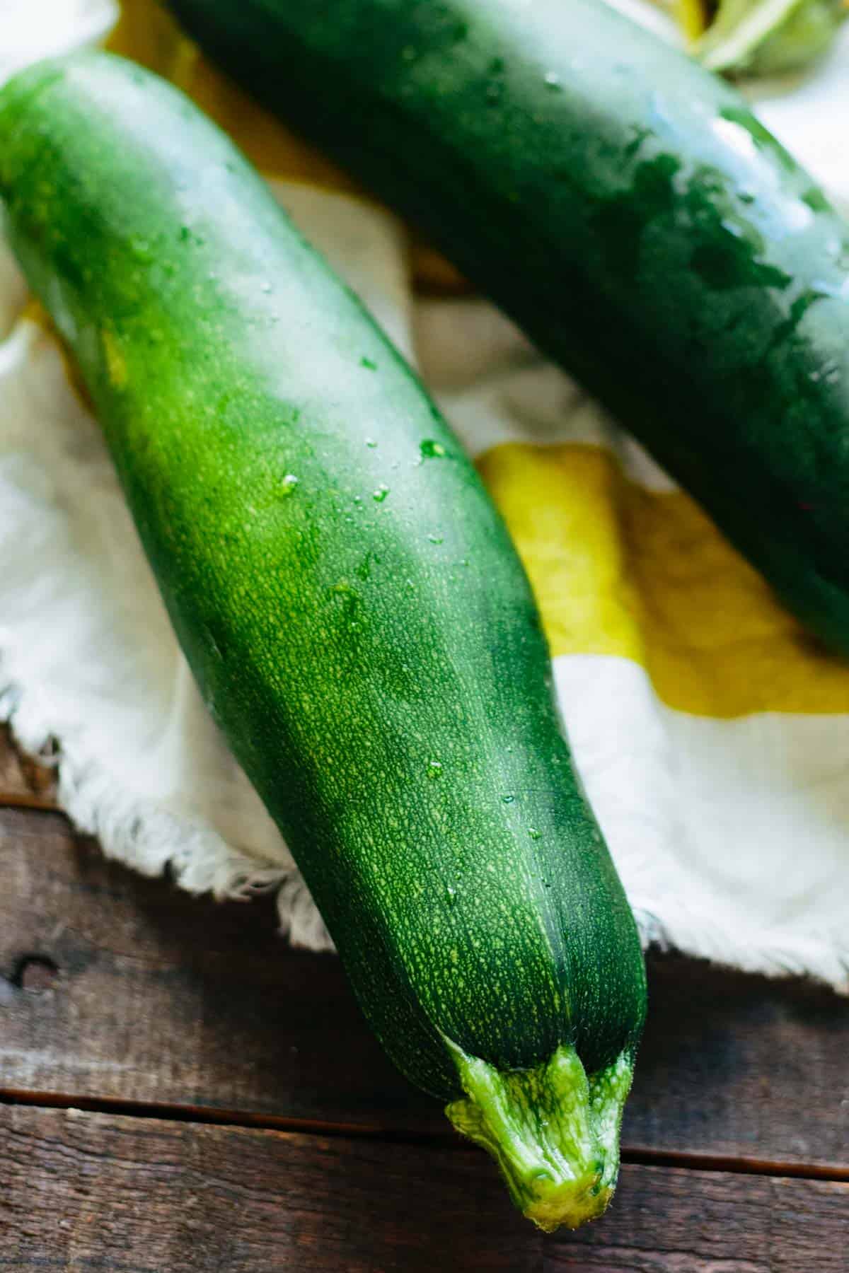 Zucchini resting on a dish towel.