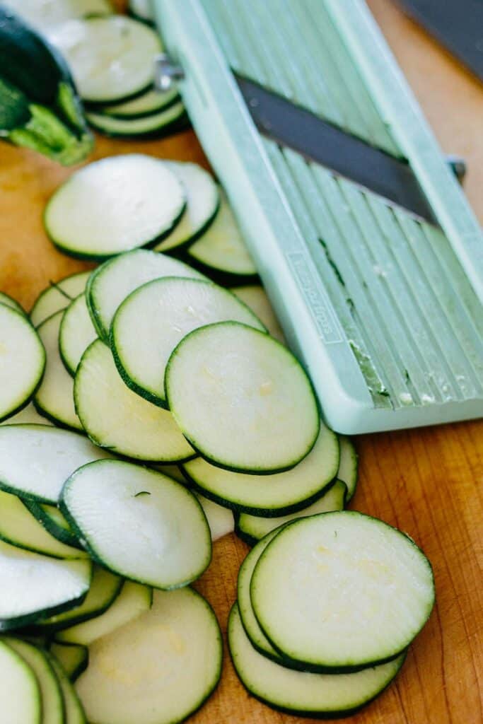 A mandolin next to a bunch of sliced zucchini