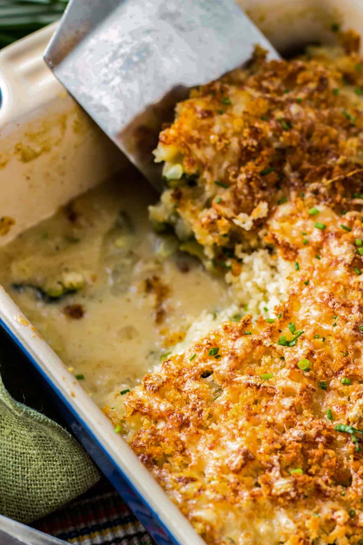 Close up of a square removed from the corner of zucchini gratin in a baking dish.