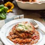 Side view of a plate of a serving eggplant parmesan with a fork.