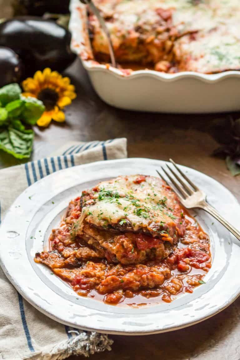 Side view of a plate of a serving eggplant parmesan with a fork.