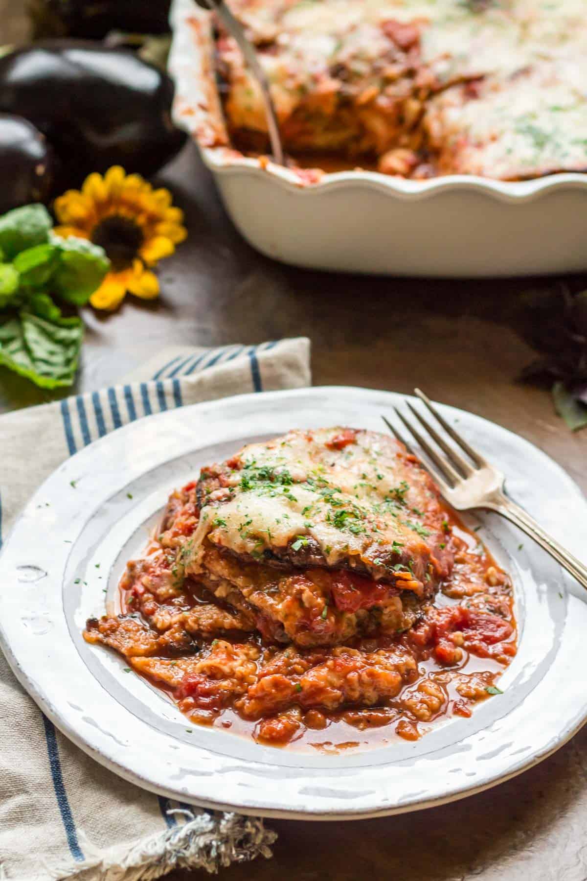 Side view of a plate of a serving eggplant parmesan with a fork.