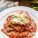 Serving of eggplant Parmesan on a white dinner plate.