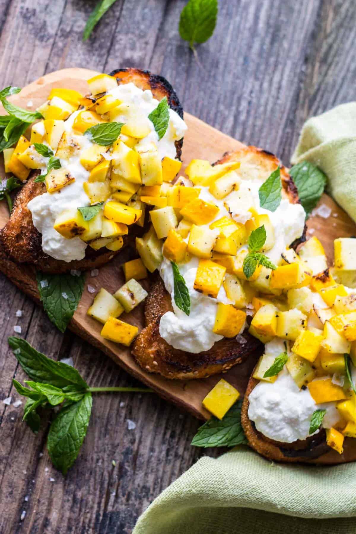 overhead shot of grilled zucchini bruschetta on a wood platter