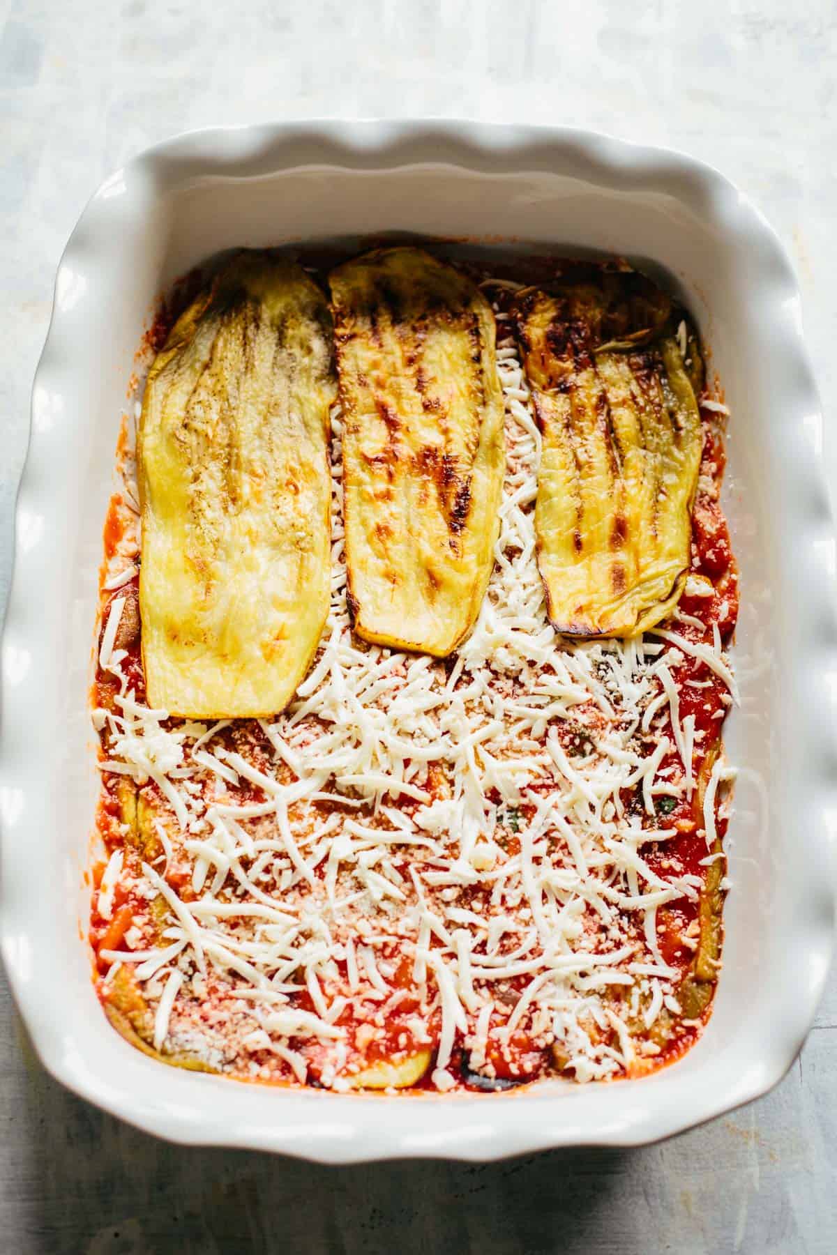 a layer of eggplant, cheese and tomato sauce in a casserole dish