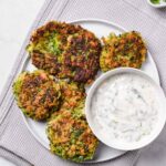 Top view of a plate of zucchini fritters with lemon herb yogurt dip.