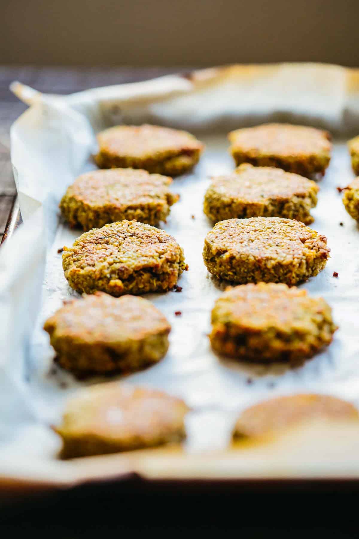 Close up of quinoa falafel on a parchment-lined baking sheet fresh out of the oven.