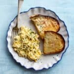 overhead shot of a plate with soft scrambled eggs and toast with a fork