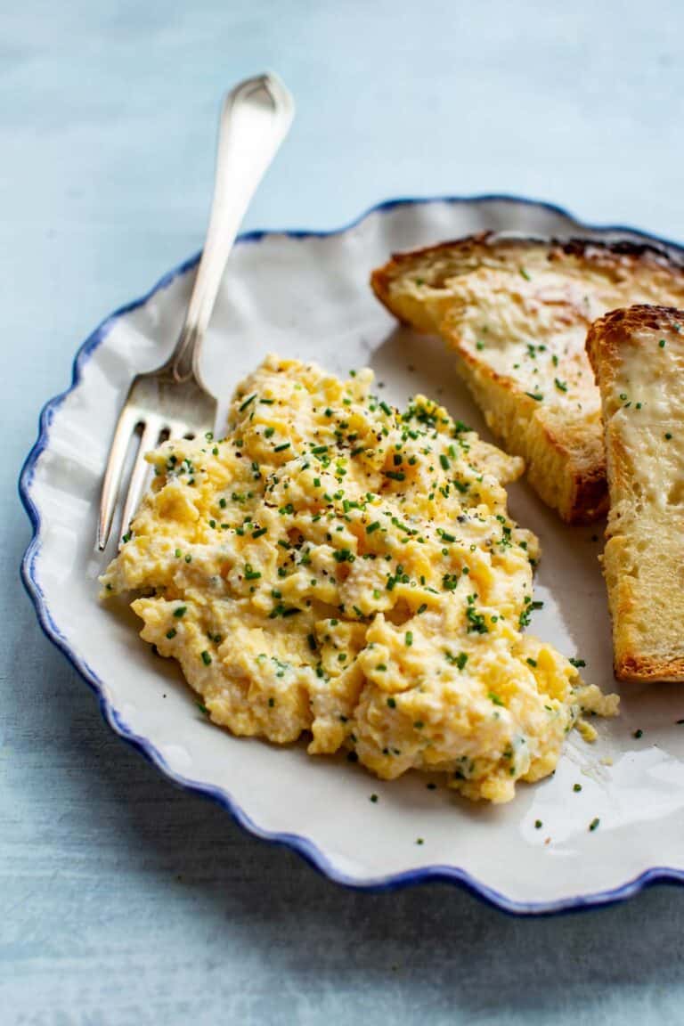 close up of soft scrambled eggs on a plate with a fork