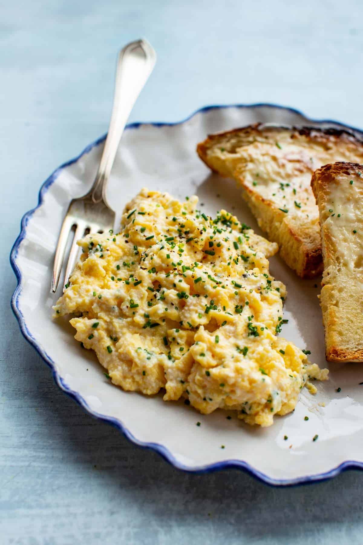 close up of soft scrambled eggs on a plate with a fork