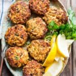 overhead shot of a platter with crab cakes and lemon wedges on top