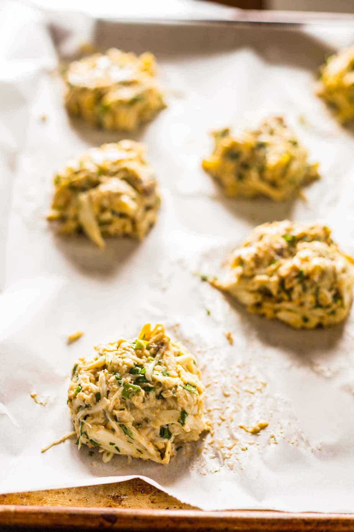Raw crab cakes on a parchment lined baking sheet.