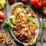 Overhead shot of a platter of tomatoes with fried onions on top.