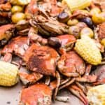 Close up of a pile of steamed crabs and corn on the cob.