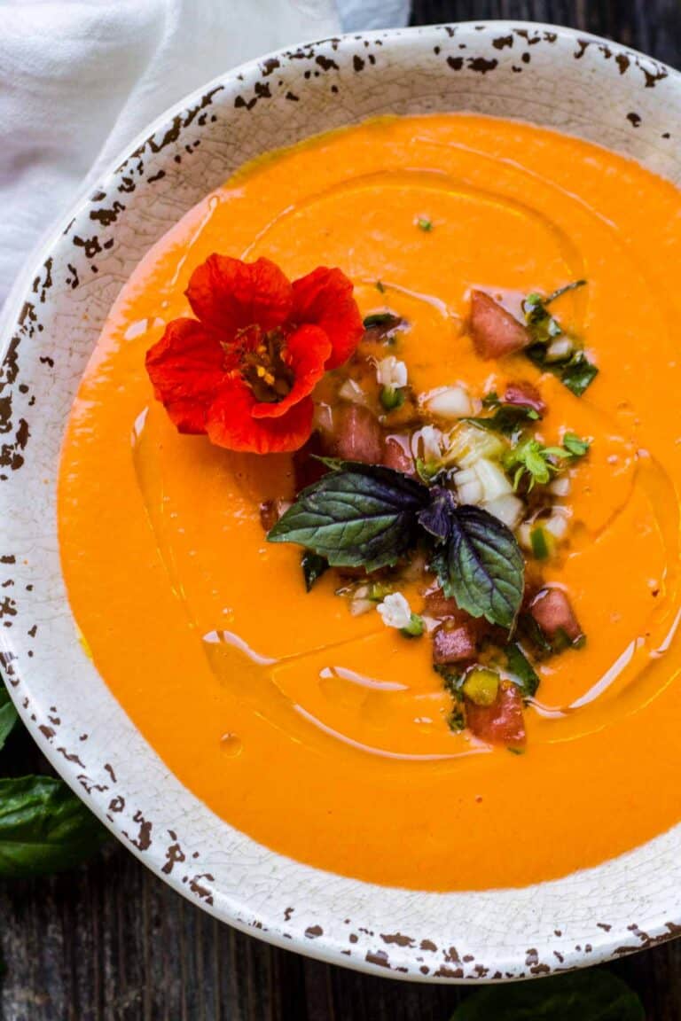 A bowl of gazpacho garnished with an edible flower.